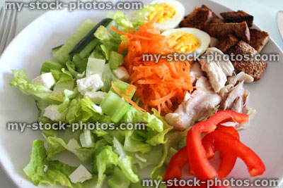 Stock image of healthy chicken salad, with boiled eggs, lettuce, carrot, cucumber, croutons