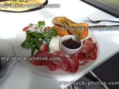 Stock image of antipasto board, prosciutto ham, salami, rocket salad, tomatoes, buffalo mozzarella, salt bread, olive tapenade