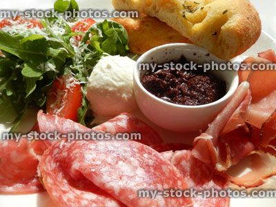 Stock image of antipasto board, prosciutto ham, salami, rocket salad, tomatoes, buffalo mozzarella, salt bread, olive tapenade