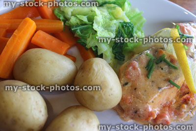 Stock image of poached salmon fillet with potatoes, carrots, cabbage, lemon herb sauce