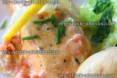 Stock image of poached salmon fillet with potatoes, carrots, cabbage, lemon herb sauce