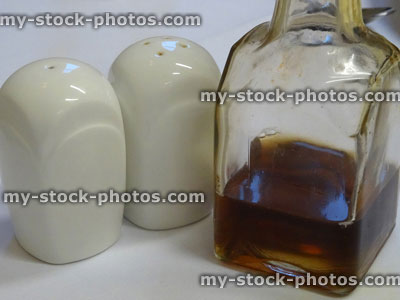 Stock image of white china, square salt / pepper pots, glass vinegar bottle, cruet set