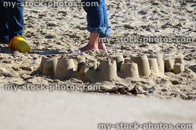 Stock image of beach sandcastles / flags at seaside, people in background