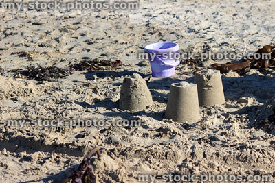 Stock image of sandcastles on seaside beach, plastic purple bucket