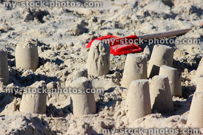 Stock image of round sandcastles on sandy beach, with red spade