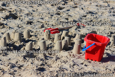 Stock image of red bucket and spade on beach, making sandcastles