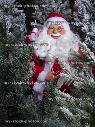 Stock image of Santa Claus toy figurine walking through Christmas tree forest