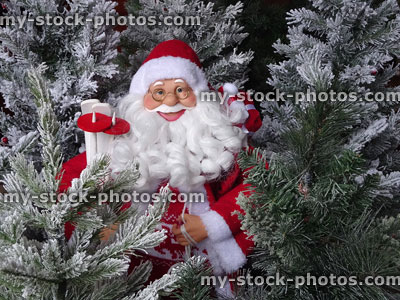 Stock image of toy Santa Claus with artificial snow covered Christmas trees