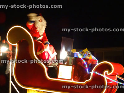 Stock image of Santa Claus in sleigh with presents, waving at children