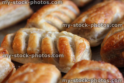 Stock image of freshly baked sausage rolls on oven tray, puff pastry