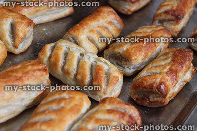 Stock image of freshly baked sausage rolls on oven tray, puff pastry