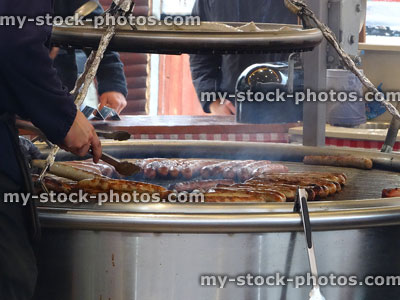 Stock image of bratwurst sausages cooking on large charcoal grill, German market