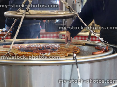 Stock image of long bratwurst sausages being cooked on barbecue grill