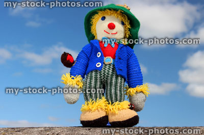 Stock image of friendly knitted scarecrow toy against sky background