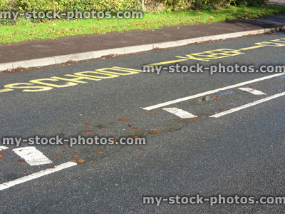 Stock image of yellow warning sign, School Keep Clear, painted tarmac road, no parking
