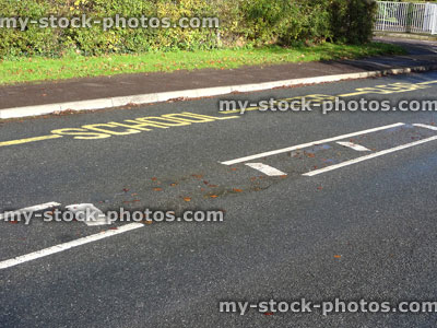 Stock image of yellow warning sign, School Keep Clear, painted tarmac road, no parking