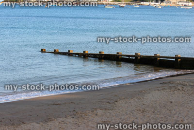 Stock image of wooden seaside groyne, sandy beach, sea defence, town, houses
