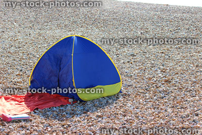 Stock image of a pebble seaside with small popup tent shelter