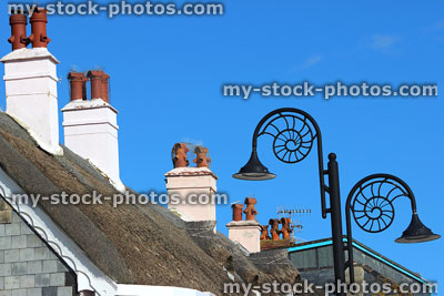 Stock image of row of thatched roofs, chimney pots, ammonite street lamps