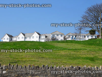 Stock image of white terraced houses on grass hilltop, slate roofs