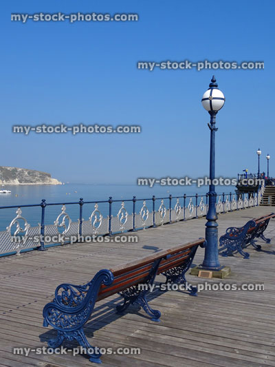 Stock image of seaside pier with wrought iron benches, lights, railings, timber decking