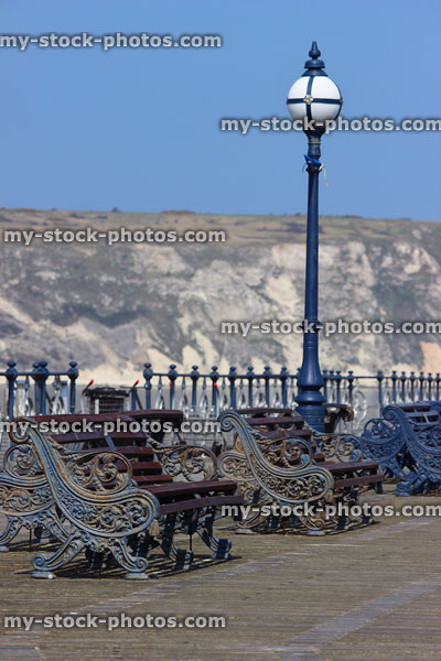 Stock image of seaside pier, chalky cliffs, wooden decking, ornate iron benches
