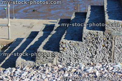 Stock image of concrete steps / staircase by seaside harbour, pebble beach