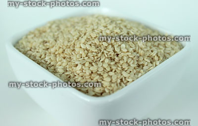 Stock image of sesame seeds piled in small square white dish