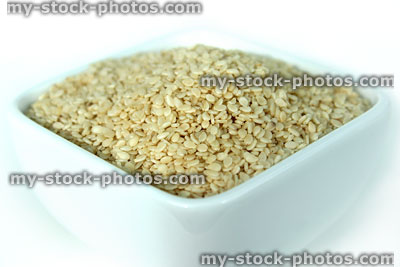 Stock image of sesame seeds in square dish, white background, health food