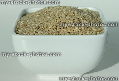 Stock image of sesame seeds in square white dish, healthy snack food