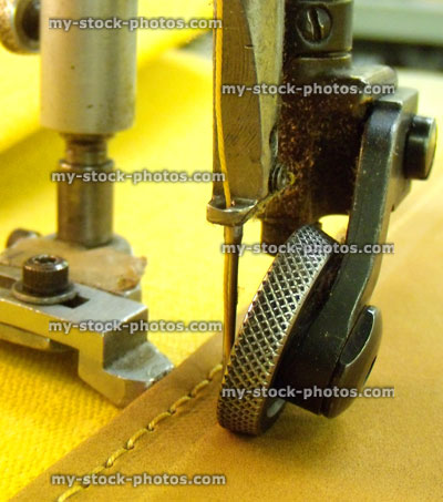 Stock image of sewing machine needle stiching yellow fabric / leather material