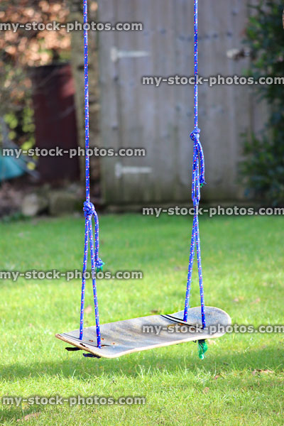 Stock image of skateboard swing tied to garden tree, upcycling project
