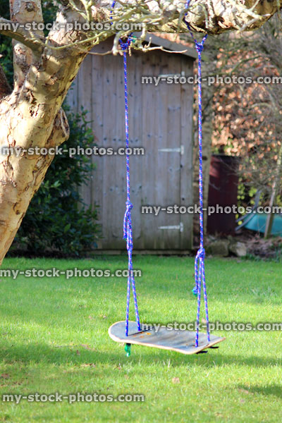 Stock image of skateboard swing tied to garden tree, recycling project