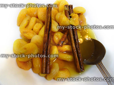 Stock image of soaked dried apricots with cinnamon sticks, healthy breakfast