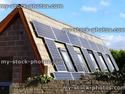 Stock image of barn conversion house with solar panels around windows, steep roof