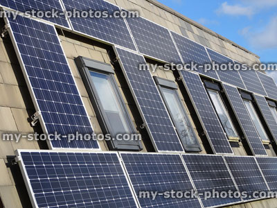 Stock image of roof with solar panel collectors around windows, sunshine