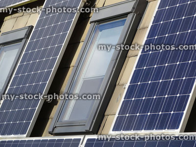 Stock image of solar panel cells around skylight windows, roof tiles