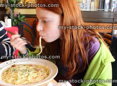 Stock image of girl eating spaghetti in carbonara sauce with grated parmesan cheese