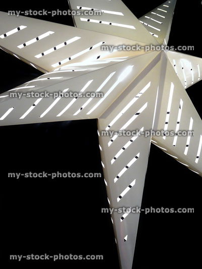 Stock image of white star shaped ceiling light hanging in dark room