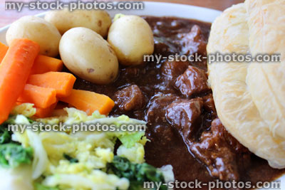 Stock image of steak and ale pie, new potatoes, carrots, cabbage, gravy, puff pastry