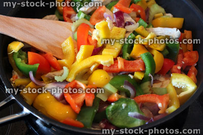 Stock image of stir fry being cooked, peppers, onions, chicken, celery, wooden spatula