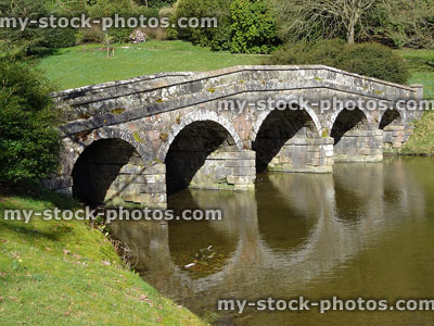 Stock image of old stone bridge with arches reflecting over river
