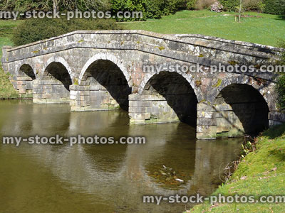 Stock image of historic stone bridge with arches reflecting in river
