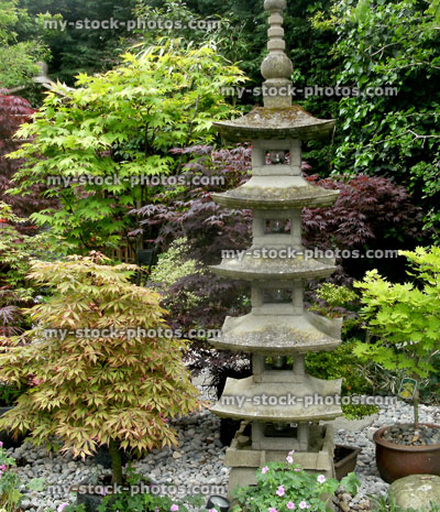 Stock image of tall Japanese stone pagoda, oriental garden with maples
