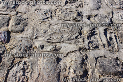 Stock image of eroded grey stone wall / concrete cement mortar pointing