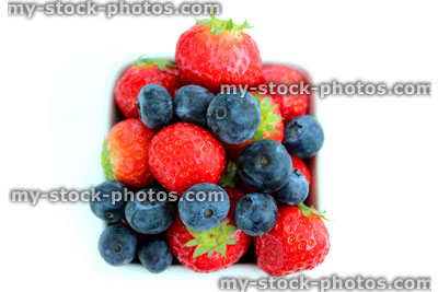 Stock image of fresh organic strawberries and blueberries, small white dish