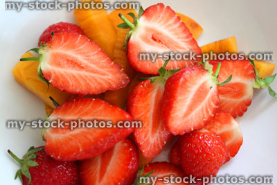 Stock image of cut strawberries with stems and persimmon fruit pieces