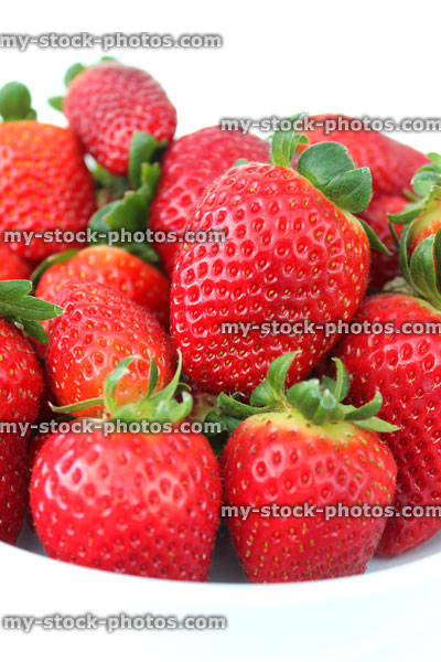 Stock image of fresh red strawberries, strawberry fruit / leaves, white dish