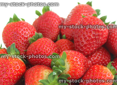 Stock image of fresh red strawberries, strawberry fruit, green stalks / leaves