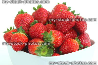 Stock image of fresh red strawberries, strawberry fruit / stalks, white dish